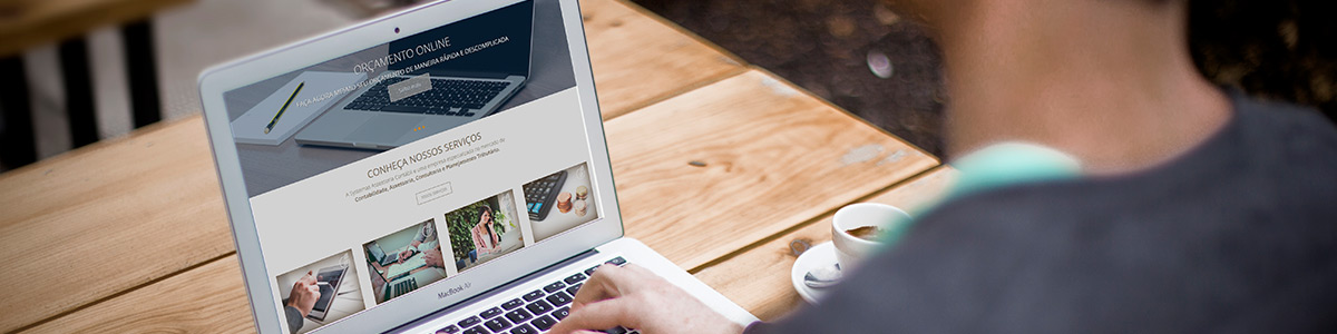 homem visitando um site de empresa contábil em um notebook e uma xícara de café sobre a mesa